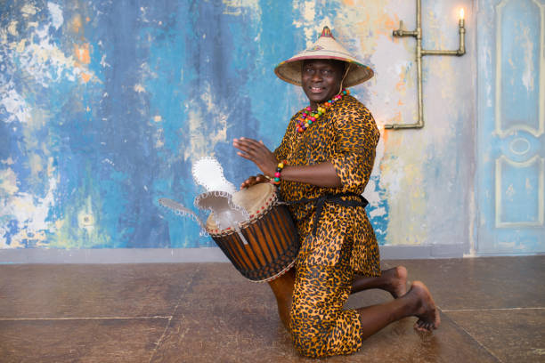 istock Handsome african drummer weared in traditional costume playing on djembe drum 1202700530