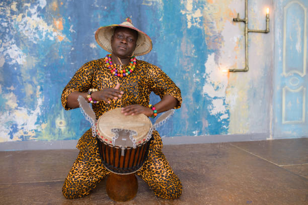 istock Handsome african drummer weared in traditional costume playing on djembe drum 1202700534
