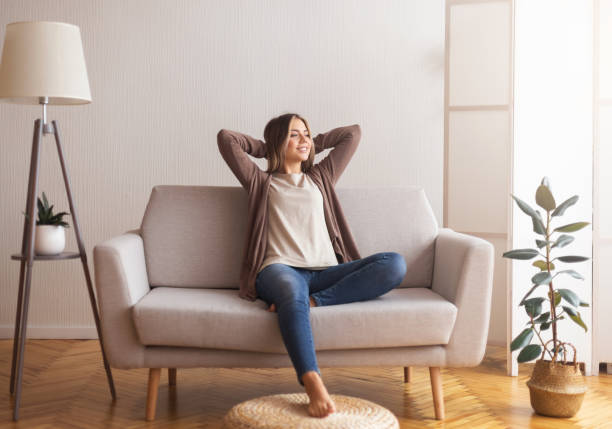 Millennial girl relaxing at home on couch Millennial girl relaxing at home on couch, enjoying weekends, empty space sitting stock pictures, royalty-free photos & images
