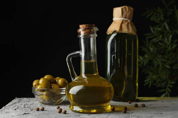 istock Bottle and jug with olive oil against black background, space for text 1202701545
