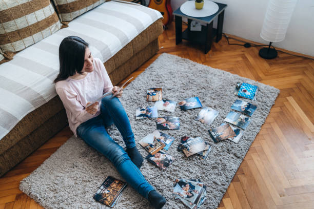 mujer mirando fotografías en casa - mirar un objeto fotos fotografías e imágenes de stock