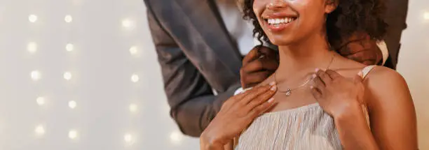 Photo of Cropped of man putting beautiful necklace on woman neck