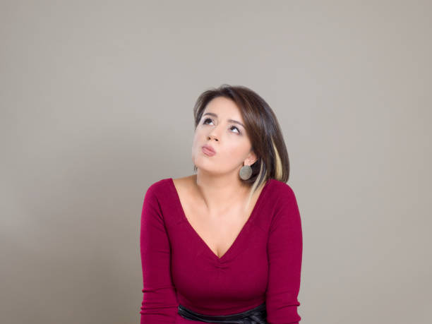 istock Mature businesswoman thinking while looking up against gray background 1202705956
