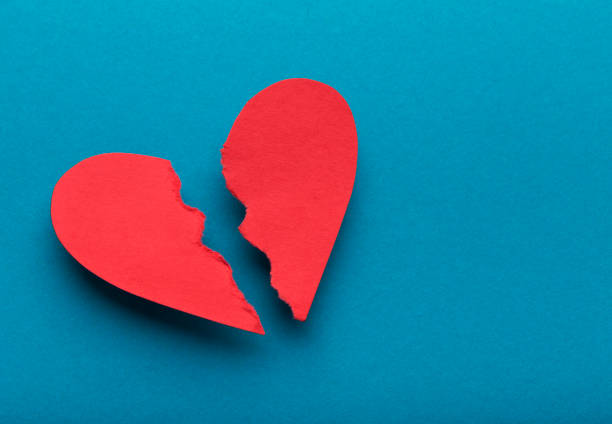 Broken paper heart on blue background, top view