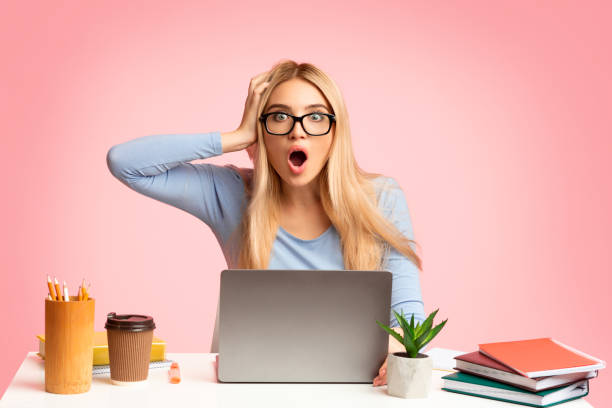 istock Blonde girl looking at camera using laptop 1202706098