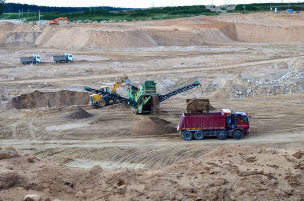 istock Wheel front-end loader loads sand into a dump truck at mining quarry 1202708800