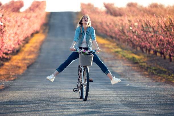 bonita mujer joven con una bicicleta vintage disfrutando del tiempo en el campo de cerezos en primavera. - happy time fotografías e imágenes de stock