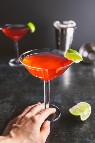 Red cocktail with lime in Martini glass on a table.