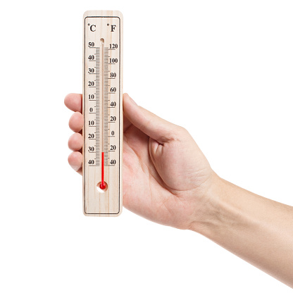Hand holding thermometer showing low temperature, isolated on white background