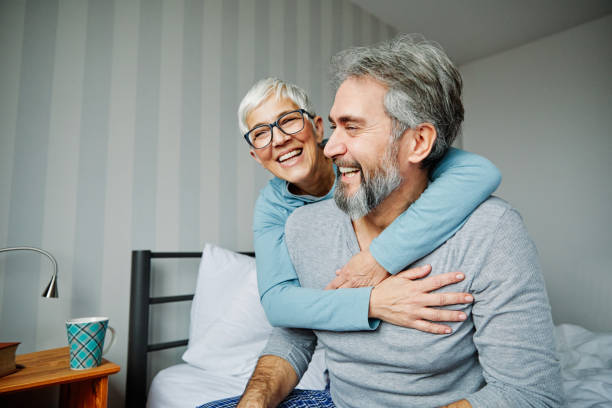 istock senior coule lying down in bed having fun laughing 1202712153