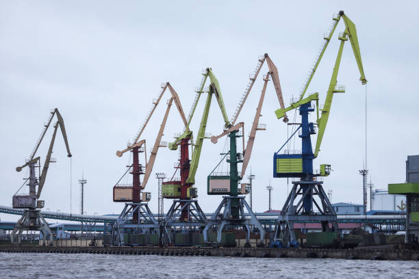 istock Port side view on big cranes in docks on a cloudy overcast day. 1202712540