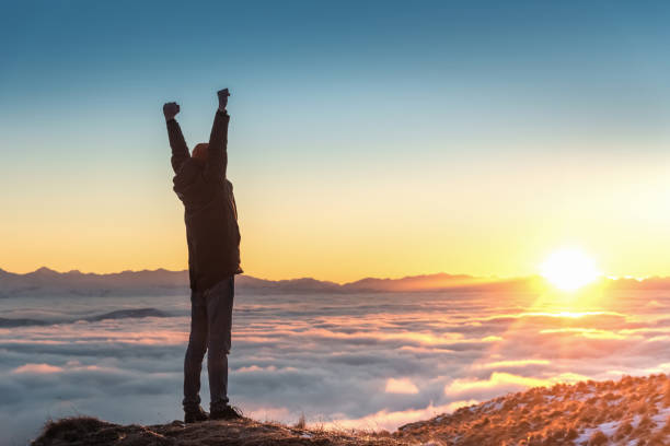 istock A man stands high in the mountains, at sunset, above the clouds. 1202716547