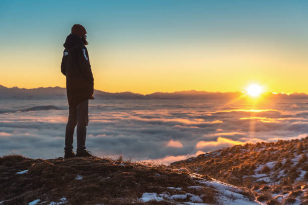 istock A man stands high in the mountains, at sunset, above the clouds. 1202716567