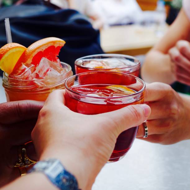 Negroni Cocktails Women cheering with Negroni cocktails on a roof top bar in London. The cocktails are garnished with an orange slice. vermouth stock pictures, royalty-free photos & images