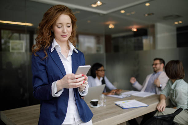 istock Young businesswoman using mobile phone and text messaging in the office 1202718612