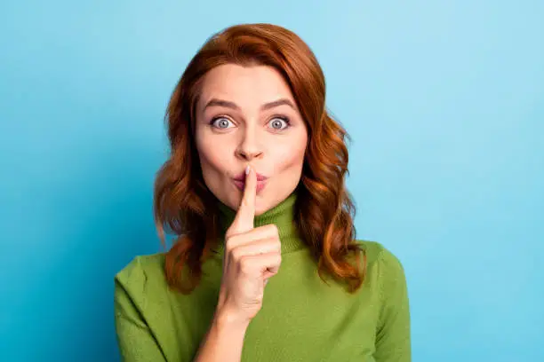 Close-up portrait of her she nice attractive lovely cheerful cheery funny funky, wavy-haired girl showing shh sign isolated over bright vivid shine vibrant green blue turquoise teal color background