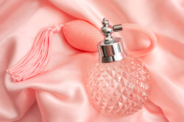 Femininity personal hygiene, retro fragrance, makeup table items and romantic scent concept theme with colorful vintage ornate flask of scented perfume on pink silk or satin background