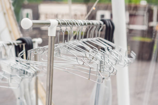 Apparel rack closeup in empty clothing store outlet with blurred background. Trendy stylish casual garment hanging in shopping center fashion boutique with no people indoors