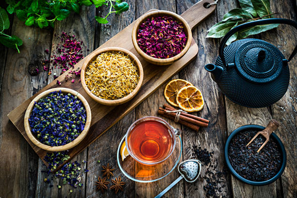 tisana: tazza da tè con varie foglie di tè essiccato e fiori girati dall'alto su un tavolo di legno rustico - homewares rustic herbal tea herb foto e immagini stock