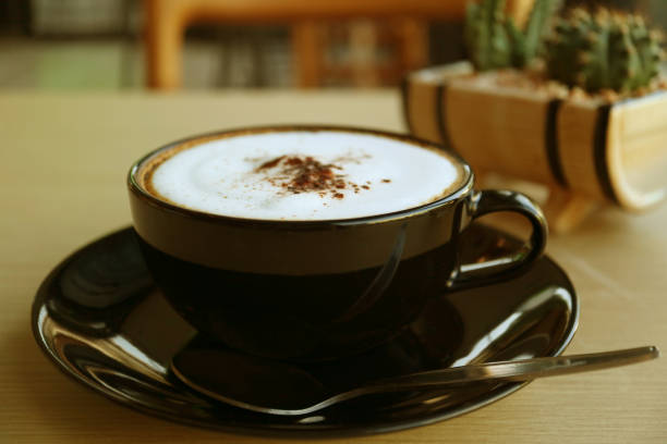 istock Cappuccino coffee in a black cup served on wooden table 1202721908