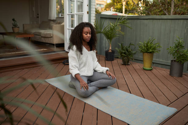 istock Young woman meditating on her patio outside 1202724948