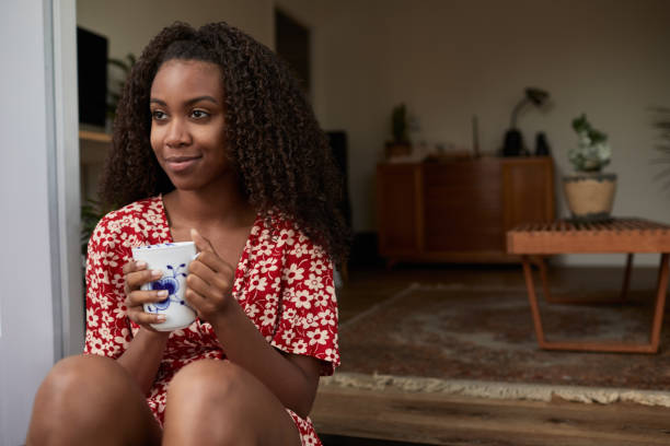 istock Young woman smiling while drinking a coffee on her patio 1202725171