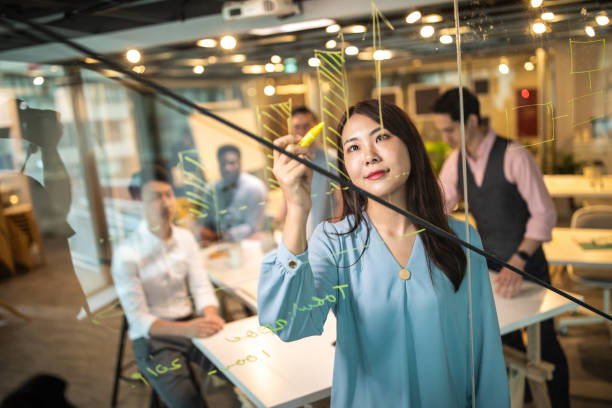 istock Sharing her business plan on transparent wipe board 1202725345