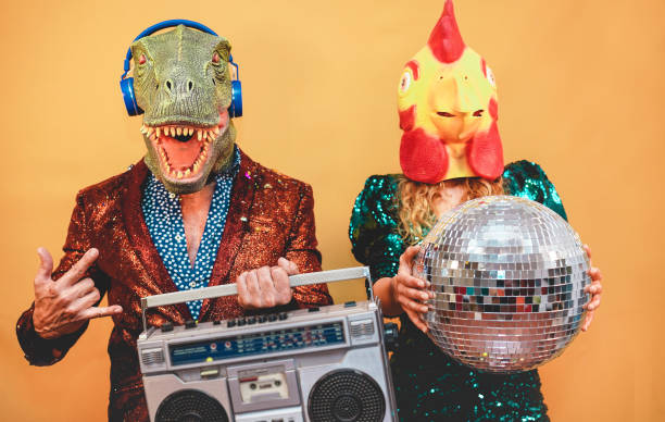 les gens élégants fous écoutant la musique avec la stéréo de boombox de cru - couple de mode utilisant le t-rex et le masque de poulet à l'événement de fest de partie - absurde, vacances et concept drôle de tendance - foyer sur le visage d'homme - male animal audio photos et images de collection