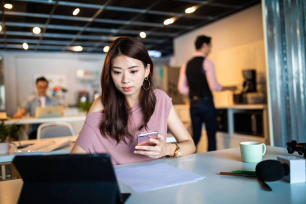 Taiwanese woman multi-tasking at modern open space workplace