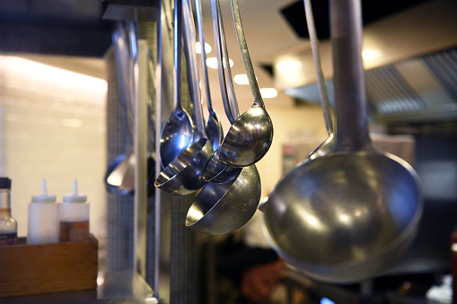 A large number of metal ladles hanging in the kitchen of the restaurant.