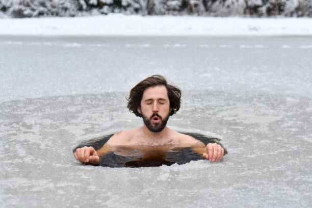 Young man have bath in cold water in nature and does Wim hof method stock photo