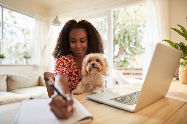 istock Smiling woman working with her dog on her lap 1202730257