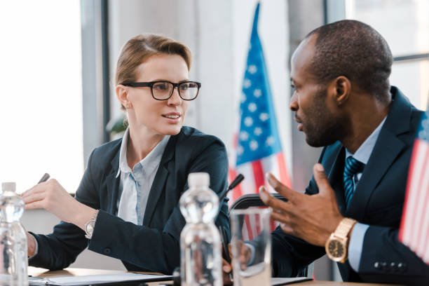selective focus of attractive diplomat talking with african american representative selective focus of attractive diplomat talking with african american representative diplomacy stock pictures, royalty-free photos & images