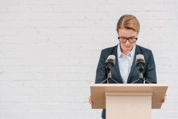 istock beautiful speaker standing near microphones and brick wall 1202731153