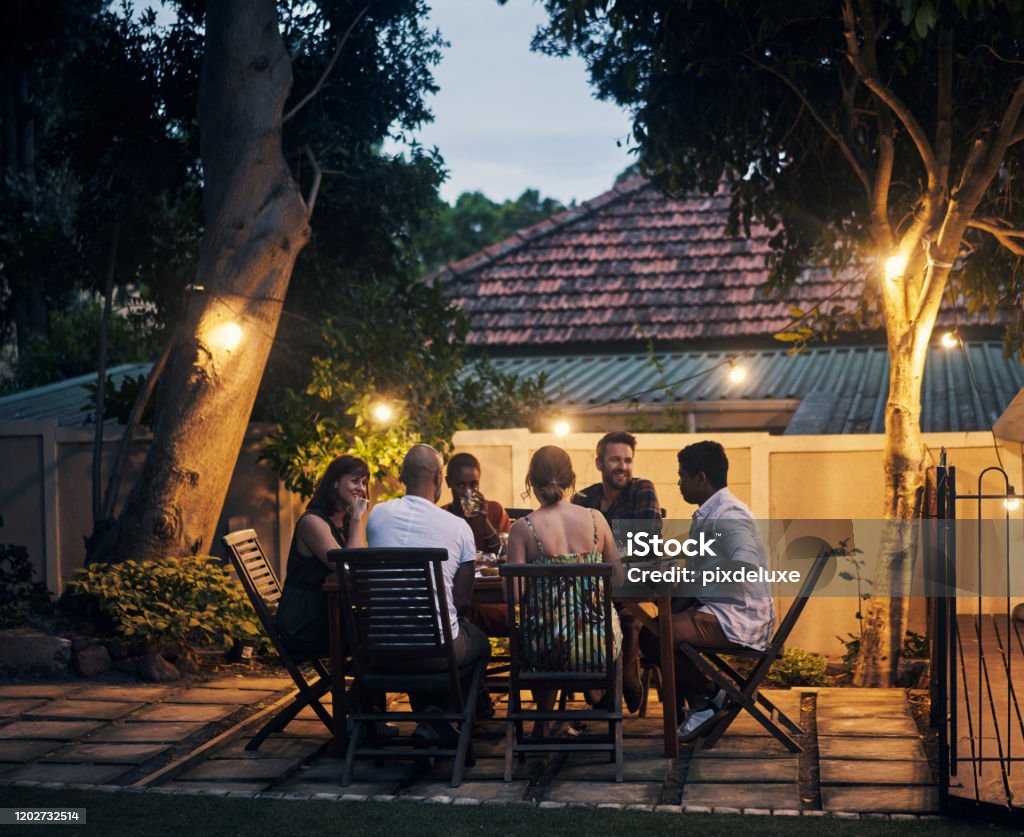 Nothing is better than food shared with friends Shot of a group of young friends having a dinner party outdoors Friendship Stock Photo