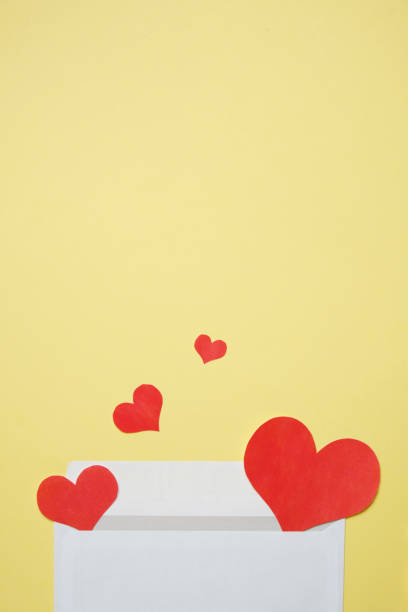 istock White envelope with flying hearts on a yellow background. Top view. 1202733175