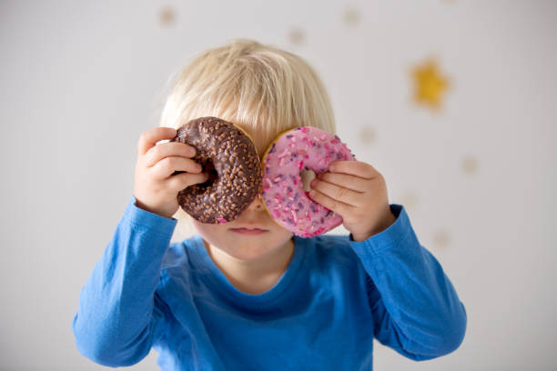 Cute sweet blonde child, playing and eating donuts Cute sweet blonde child, playing and eating donuts at home overweight boy stock pictures, royalty-free photos & images