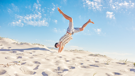 Shot of a handsome young man having fun in the sand