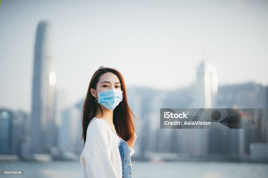 Young Asian woman wearing a protective face mask to prevent the spread of coronavirus, a global health emergency over outbreak Young Asian woman wearing a protective face mask to prevent the spread of coronavirus in the city, a global health emergency over outbreak Asian and Indian Ethnicities Stock Photo
