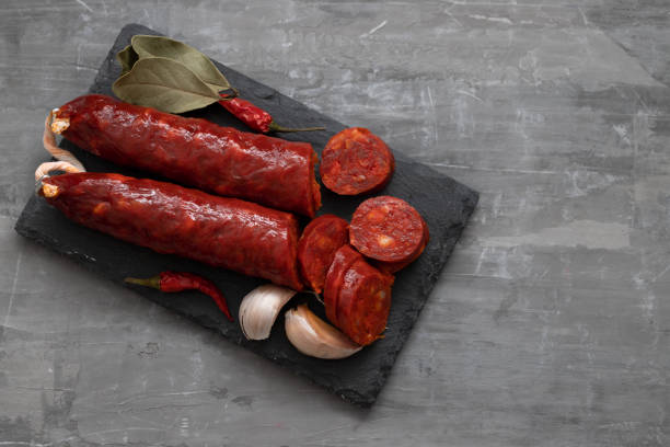 испанская копченая колбаса чоризо на черной керамической доске - chorizo стоковые фото и изображения