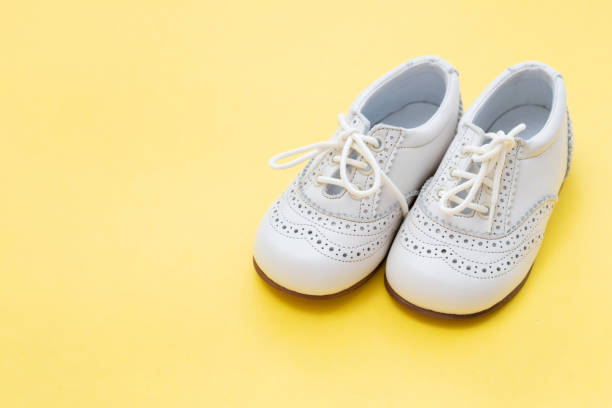 istock white baby shoes on yellow background 1202740205