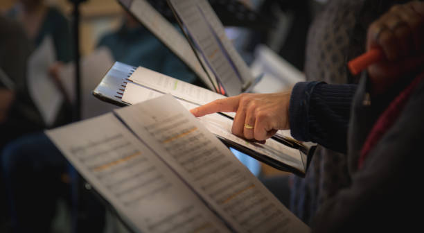 Hand, finger and music sheet Hand points to notes during choir rehearsal, shallow depth of field choir photos stock pictures, royalty-free photos & images