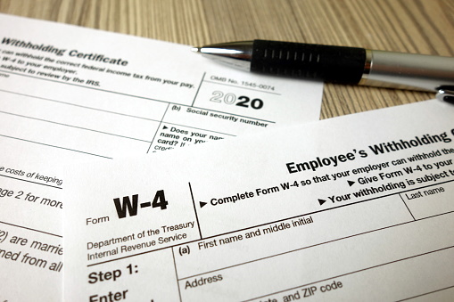 Blank W-4 form and a pen. Tax season concept