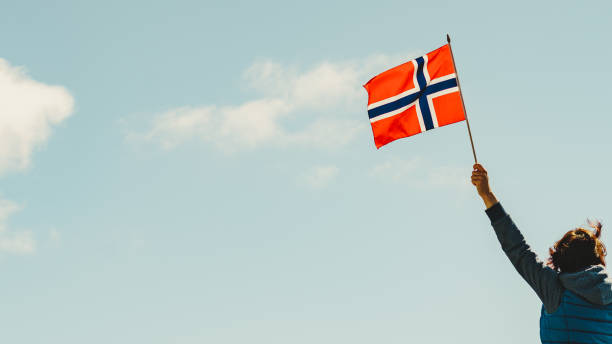 istock Hand holds norwegian flag against sky 1202742691