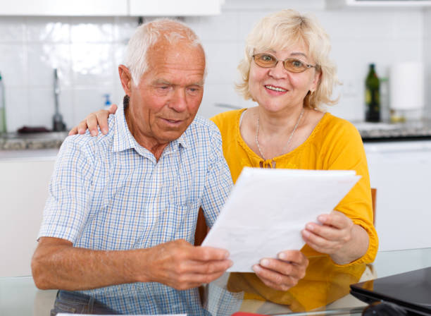 istock Happy mature couple with documents sitting at table in home 1202742724