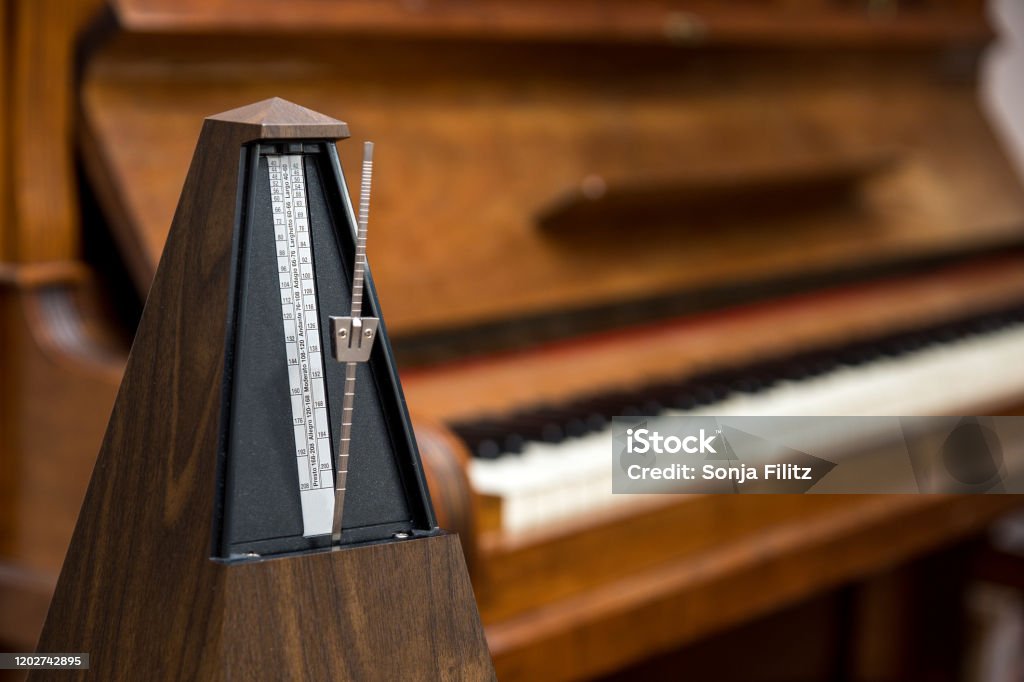 metronome in front of an old piano old, analog metronome, in front of an old piano in the background. Selective sharpness Metronome Stock Photo
