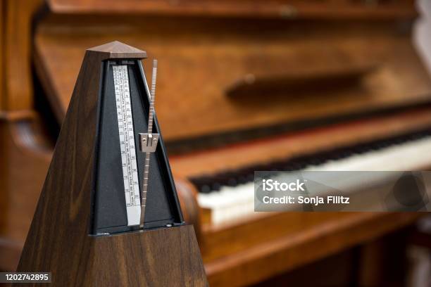 Metronome In Front Of An Old Piano Stock Photo - Download Image Now - Metronome, Piano, Rhythm