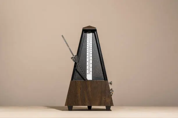 old, analog metronome, isolated against a concrete background with space for text