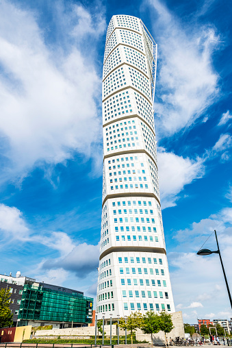 Malmö, Sweden - August 30, 2019: Turning Torso, neo-futurist residential skyscraper designed by Santiago Calatrava with people around in Malmo, Sweden