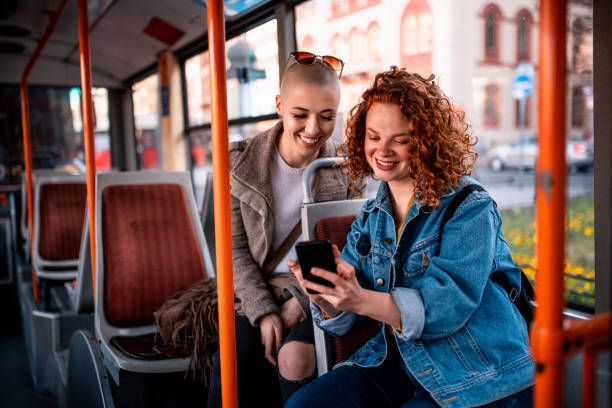 due giovani donne che leggono sms sull'autobus - autobus italy foto e immagini stock